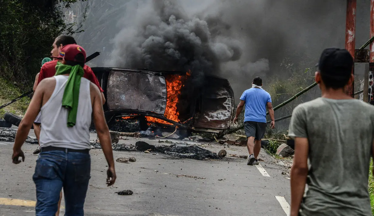 Demonstran dari oposisi Venezuela membuat barikade dengan membakar mobil saat menggelar aksinya menentang Presiden Nicolas Maduro di Caracas, Venezuela (24/4). (AFP/Federico Parra)