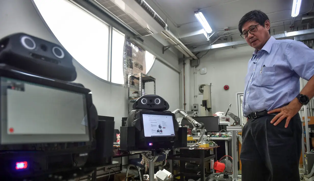 Profesor Viboon Sangveraphunsiri berdiri dekat robot medis yang dimodifikasi untuk memeriksa pasien virus corona COVID-19 di Regional Center of Robotics Technology, Chulalongkorn University, Bangkok, Thailand, Rabu (18/3/2020). Robot dikerahkan membantu memerangi COVID-19. (LILLIAN SUWANRUMPHA/AFP)