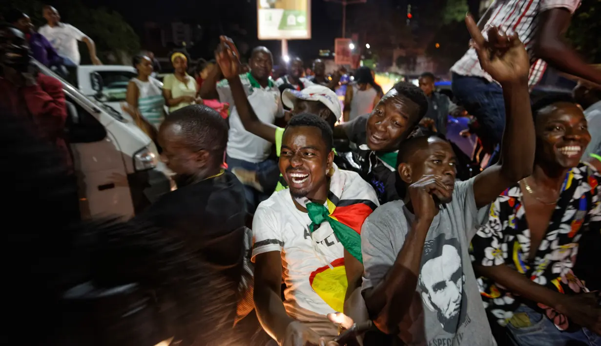 Warga Zimbabwe bernyanyi menyambut kabar Presiden Robert Mugabe mengundurkan diri di sebuah persimpangan pusat kota Harare, Selasa (21/11). Mugabe sebelumnya menolak untuk mengundurkan diri, meski ada pengambilalihan militer pekan lalu. (AP/Ben Curtis)