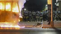 Polisi berdiri dekat truk sampah yang terbakar saat protes di Kenosha, Wisconsin, Amerika Serikat, Senin (24/8/2020). Protes dipicu oleh penembakan Jacob Blake oleh petugas polisi Kenosha sehari sebelumnya. (AP Photo/Morry Gash)