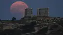 Bulan Purnama Stroberi atau Strawberry Full Moon muncul di belakang Kuil Poseidon marmer kuno di Cape Sounion, sekitar 70 Km selatan kota Athena, Yunani, Kamis (24/6/2021). Strawberry Full Moon adalah istilah yang diambil dari cerita tradisi dari suku-suku asli Amerika (AP Photo/Petros Giannakouris)