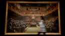 Petugas melintas di depan lukisan seniman jalanan Banksy yang dipajang di ruang lelang Sotheby, London, Jumat (27/9/2019). Lukisan tersebut pernah dipajang di pameran 'Banksy vs Bristol Museum' pada 2009 dan menarik lebih dari 300 ribu pengunjung. (AP/Kirsty Wigglesworth)