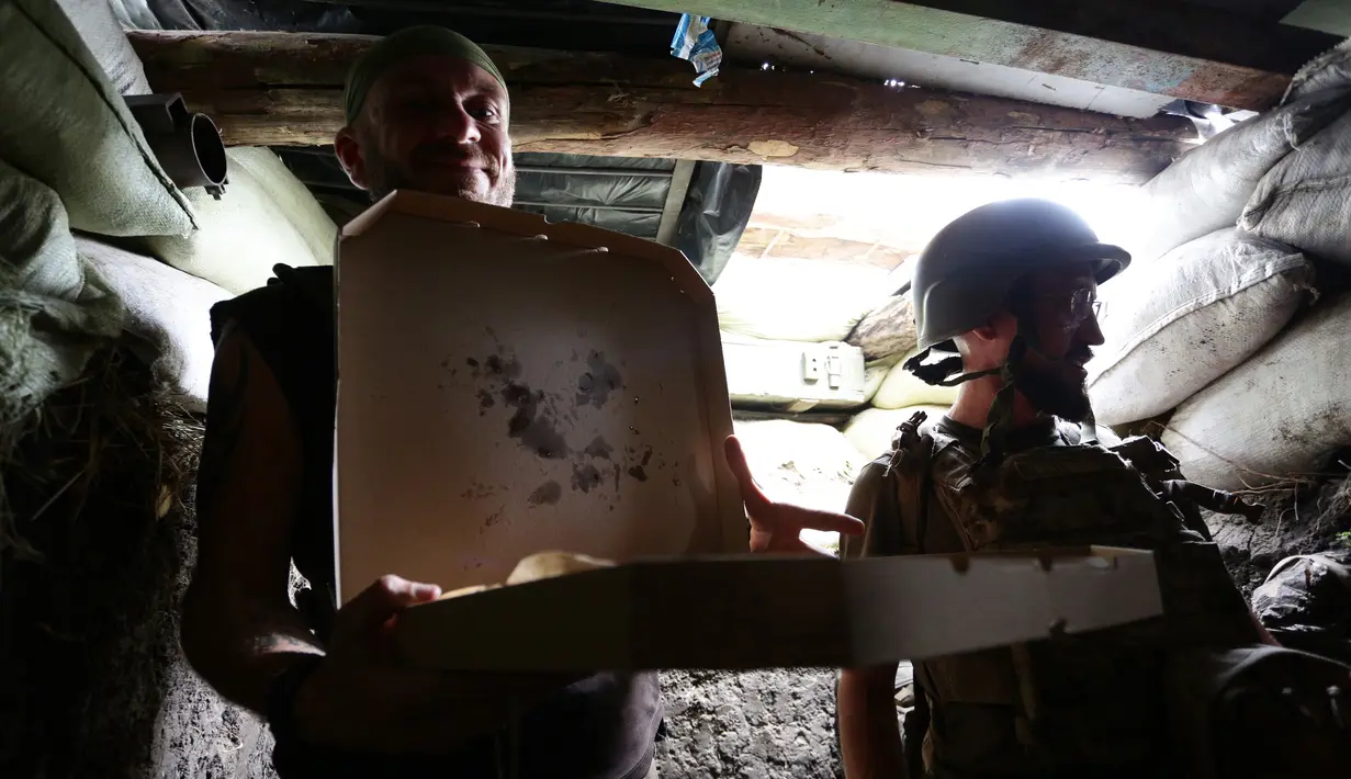 Seorang tentara Ukraina yang sedang menghadapi separatis pro-Rusia di wilayah timur negeri itu, memegang sekotak pizza yang diantarkan oleh Aleksey Kachko, salah satu pemilik kedai Pizza Veterano di Mariupol, 19 Juli 2018. (AFP/Aleksey FILIPPOV)