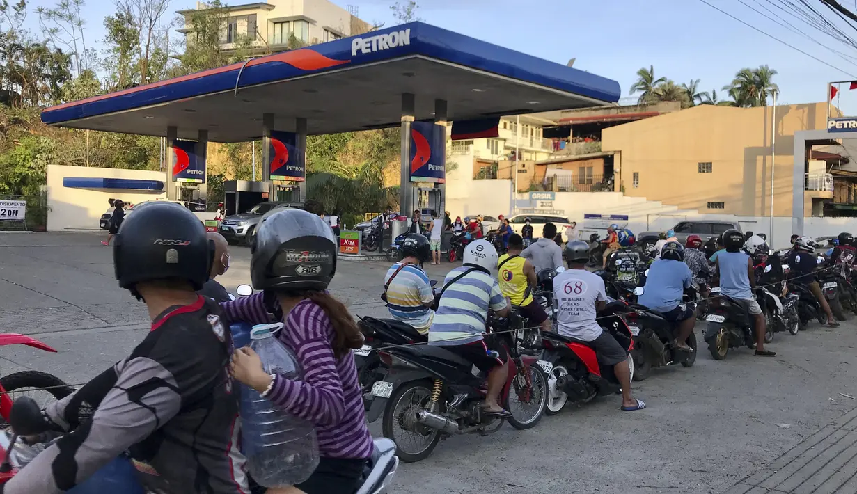 Warga mengantre untuk membeli bensin setelah Topan Rai merusak sebagian kota Cebu, Filipina, Sabtu (18/12/2021). Presiden Duterte diperkirakan akan melakukan perjalanan ke daerah-daerah yang dilanda topan, termasuk Surigao, tempat Rai mendarat pada hari Sabtu. (AP/Jay Labra)