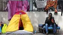 Seorang imigran terlihat menikmati cemilan di sebuah kamp darurat di jalanan Kota Paris, Prancis, Selasa (6/9). Para imigran berkulit hitam tersebut hidup terlantar di pinggir jalan kota tersebut. (REUTERS/Benoit Tessier)
