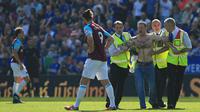 Petugas keamanan menangkap suporter yang trun ke dalam lapangan saat laga Leicester City melawan West Ham Unitd di King Power Stadium, Leicester, (5/5/2018).  West Ham menang 2-0. (AFP/Lindsey Parnaby)
