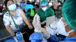 Seorang petugas kesehatan (kanan) bersiap untuk memberikan vaksin virus corona COVID-19 AstraZeneca di klinik vaksinasi massal darurat di Denpasar, Bali, Selasa (6/7/2021). Indonesia tengah memerangi gelombang infeksi baru yang belum pernah terjadi sebelumnya. (SONNY TUMBELAKA/AFP)
