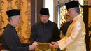 Muhyiddin Yassin (kiri) menerima dokumen dari Raja Sultan Abdullah Sultan Ahmad Shah (kanan) sebelum disumpah sebagai Perdana Menteri Malaysia di Istana Negara, Kuala Lumpur, Minggu (1/3/2020). Muhyiddin Yassin resmi menjadi PM Malaysia. (MASZUANDI ADNAN/MALAYSIA'S DEPARTMENT OF INFORMATION/AFP)