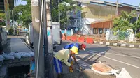 Petugas memperbaiki saluran air di lingkungan GOR Dimyati. (Liputan6.com/Pramita Tristiawati)