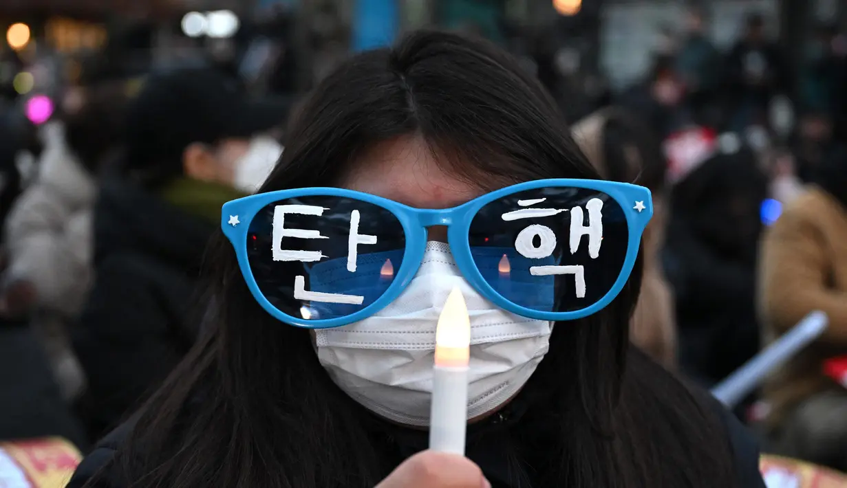 Seorang pengunjuk rasa mengenakan kacamata bertuliskan “Pemakzulan” dalam sebuah demonstrasi yang menuntut pengunduran diri Presiden Yoon Suk Yeol di luar Majelis Nasional, Seoul, Korea Selatan pada tanggal 10 Desember 2024. (Jung Yeon-je/AFP)