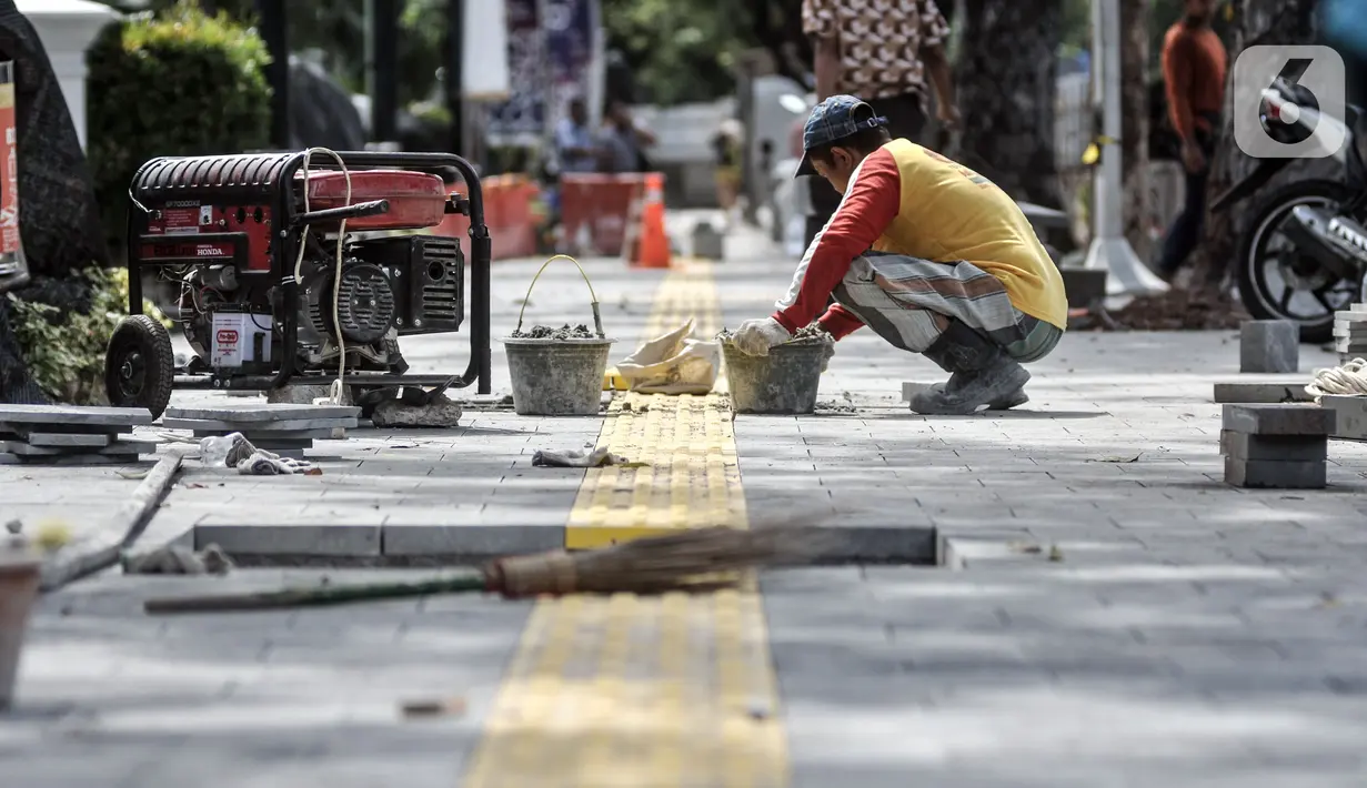 Pekerja menyelesaikan proyek revitalisasi trotoar di Jalan Medan Merdeka Selatan, Jakarta Pusat, Selasa (22/11/2022). Pemprov DKI Jakarta mengalokasikan anggaran sebesar Rp 171 miliar dalam Rancangan Anggaran Pendapatan dan Belanja Daerah (RAPBD) DKI Jakarta 2023 untuk revitalisasi trotoar di Ibu Kota. (merdeka.com/Iqbal S. Nugroho)