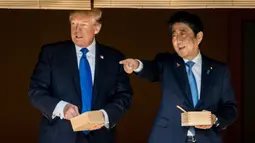 Presiden AS Donald Trump dan PM Jepang Shinzo Abe berbincang sambil memberi makan ikan di kolam koi Istana Akasaka, Tokyo, Senin (6/11). Beragam momen terlihat dalam kunjungan Presiden Donald Trump ke Jepang. (AP/Andrew Harnik)