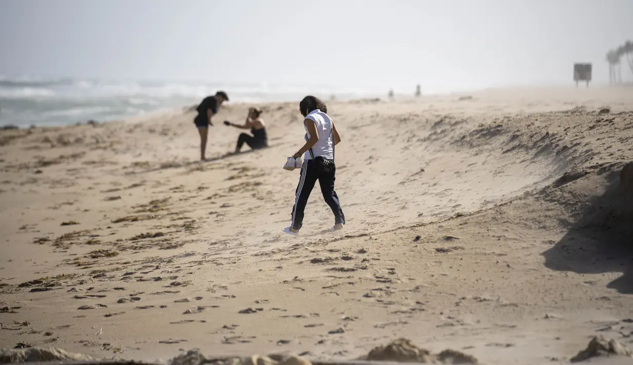 Beberapa orang bertahan dengan angin kencang di pantai di Palm Beach, Florida, Selasa, 8 November 2022, saat Badai Tropis Nicole terus meningkat kekuatannya dan diperkirakan akan mendarat di sepanjang pantai timur Florida Kamis pagi. (Foto AP/Andrew Harnik)
