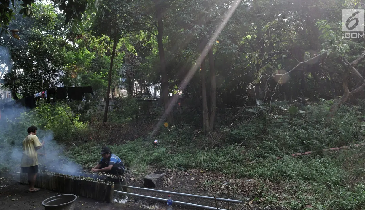 Pak Pian ditemani Pak Bambang saat memasak lemang di sebuah tanah kosong di Jakarta, Minggu (27/5). Untuk memasak lemang dapat membutuhkan waktu hingga 3 jam dengan cara dibakar. (Merdeka.com/Iqbal S Nugroho)