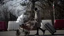 Seorang wanita mendorong kereta bayi setelah melintasi perbatasan Rumania-Ukraina, di Siret, Rumania (25/2/2022). Warga meninggalkan negara mereka ketika Rusia menggempur ibu kota Kiev dan kota-kota lain dengan serangan udara untuk hari kedua pada hari Jumat (25/2). (AP Photo/Alexandru Dobre)