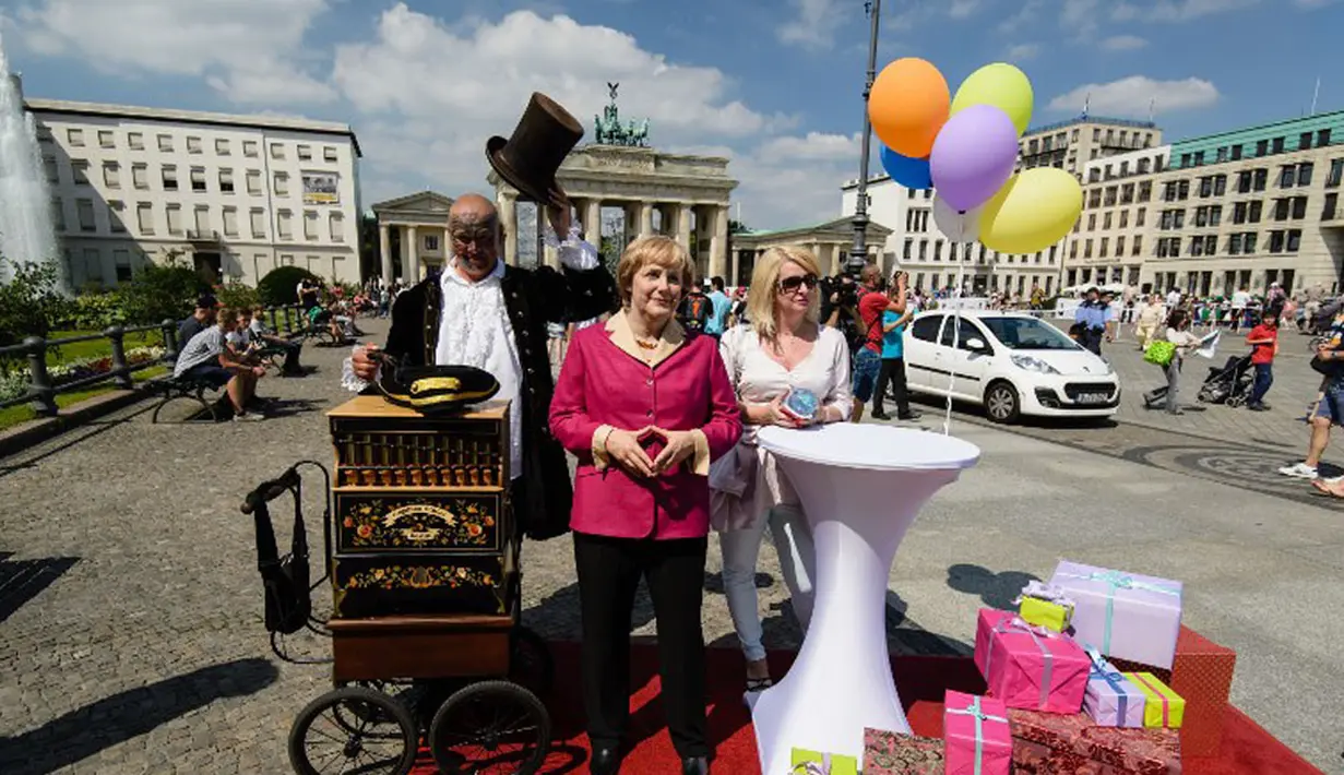 Keberadaan patung lilin Angela Merkel, di depan gerbang Brandenburg di Berlin, (16/7/2014), mengundang minat wisatawan untuk berpose di samping replika Kanselir Jerman. (AFP PHOTO/Clemens Bilan)