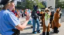 Peserta mengenakan kostum binatang berinteraksi dengan polisi saat parade konvensi Eurofurence di Berlin, Jerman (17/8). Sekitar 2700 delegasi dari berbagai negara ikut berpartisipasi dalam acara tersebut. (AFP Photo/Ganjil Andersen)