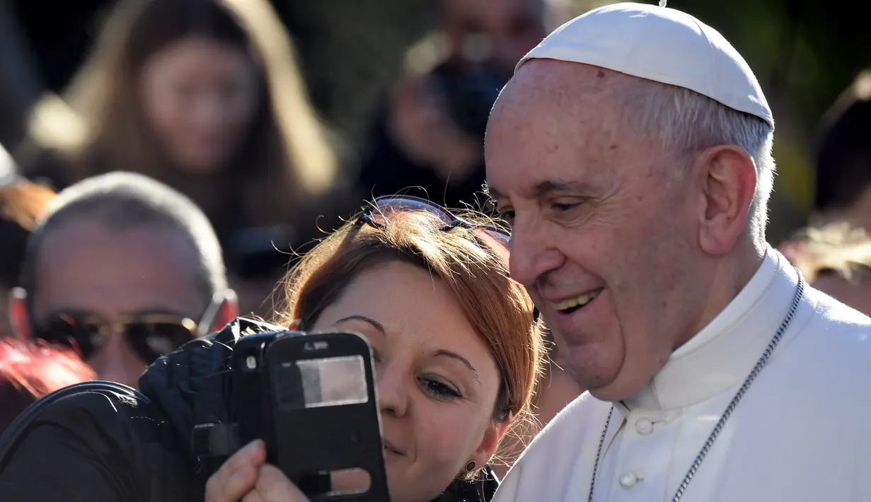 Seorang wanita mengambil foto selfie bersama Paus Fransiskus dalam kunjungannya ke St Mary Josefa di Roma, Italia, Minggu (19/2). (AFP Photo/TIZIANA FABI)
