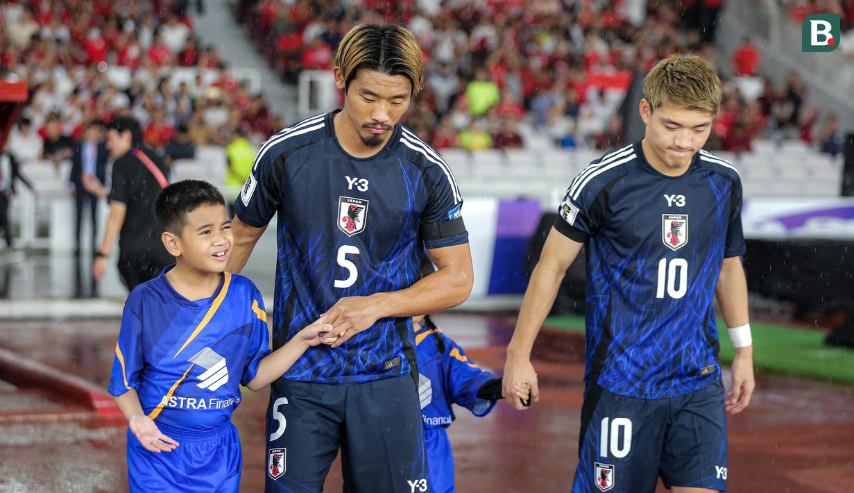 <p>Pemain Jepang, Hidemasa Morita (kedua kiri) menuntun anak kecil yang ditugaskan sebagai player escort dalam pertandingan lanjutan putaran ketiga Grup C Kualifikasi Piala Dunia 2026 melawan Timnas Indonesia di Stadion Utama Gelora Bung Karno (SUGBK), Senayan, Jakarta, Jumat (15/11/2024). (Bola.com/Bagaskara Lazuardi)</p>