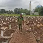 Petugas berjalan di antara makam jenazah dengan protokol COVID-19 di TPU Bambu Apus, Jakarta Timur, Selasa(16/2/2021). Pemangkasan petak makam di TPU Bambu Apus tersebut dilakukan agar bisa menampung lebih banyak jenazah, mengingat lahan pemakaman terbatas. (Liputan6.com/Herman Zakharia)