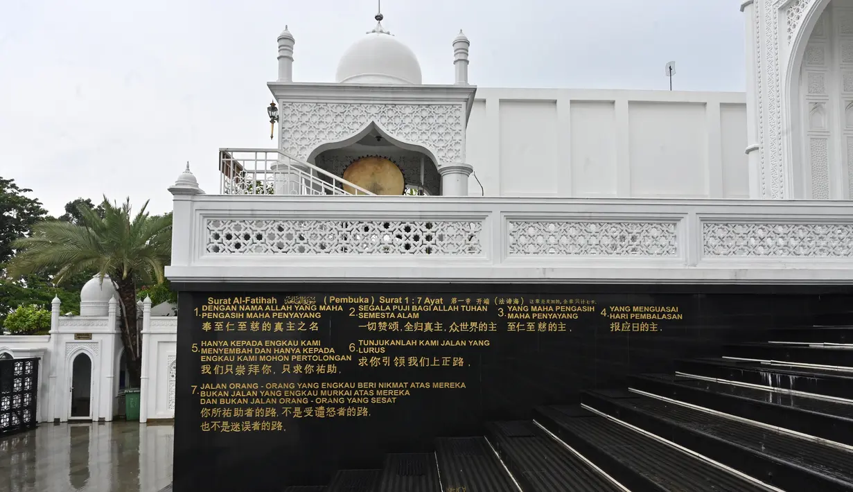 Terjemahan Surat Al-Fatihah terlihat dalam bahasa Inggris, Bahasa Indonesia dan aksara China di dinding menuju masjid Ramlie Musofa yang kosong selama bulan suci Ramadan karena pandemi virus coronavirus COVID-19 di Jakarta (4/5/2020). (AFP/Adek Berry)