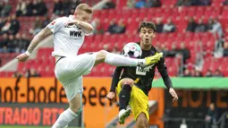 Pemain Borussia Dortmund, Giovanni Reyna, berebut bola dengan pemain Augsburg, Andre Hahn, pada laga Bundesliga, Minggu (27/9/2020). Augsburg menang dengan skor 2-0. (Matthias Balk/dpa via AP)