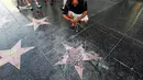 Pengunjung mengambil gambar bintang di Walk of Fame Hollywood atas nama Presiden AS Donald Trump yang dirusak seorang pria, di Los Angeles, Rabu (25/7). Bagian tengah bintang yang berwarna merah itu telah menjadi serpihan pasir dan batu. (AP/Reed Saxon)