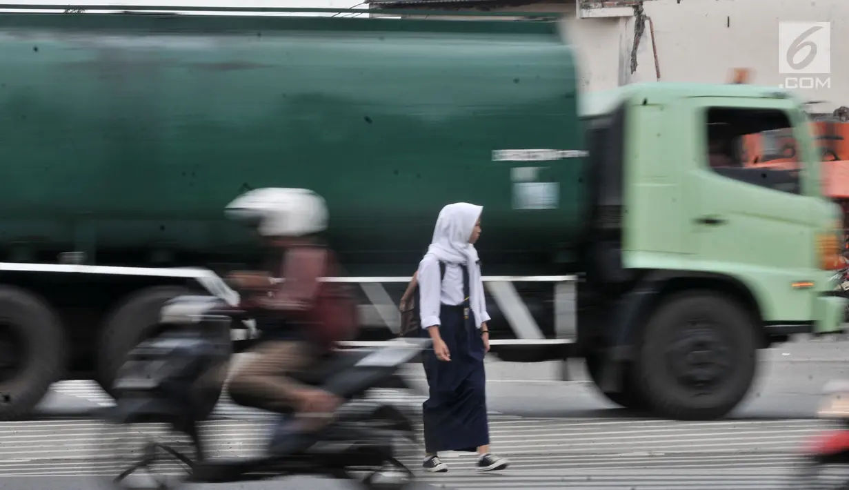 Seorang siswi dengan hati-hati menyeberangi jalan di persimpangan Terminal Pulo Gadung, Jakarta, Rabu (5/9). Menurut warga setempat, kecelakaan hampir setiap hari terjadi di persimpangan ini. (Merdeka.com/Iqbal Nugroho)