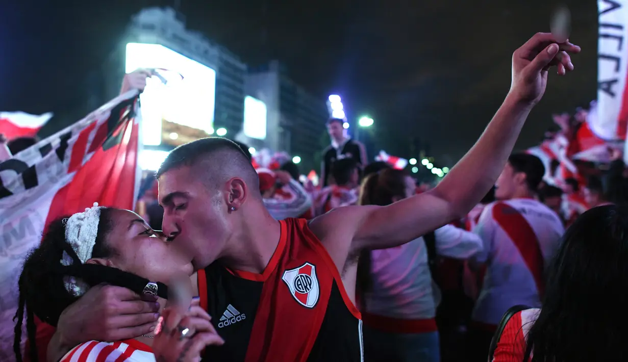 Suporter River Plate berciuman saat merayakan gelar juara Copa Libertadores di Obelisk, Buenos Aires, Argentina, Minggu (9/12). River Plate merebut gelar juara Copa Libertadores usai menaklukkan Boca Juniors dengan skor 3-1. (AP Photo/Gustavo Garello)
