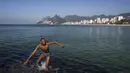 Seorang pria berjalan di daerah berbatu di pantai Arpoador selama gelombang panas di Rio de Janeiro, Brasil, pada hari libur kota Saint Sebastian, Kamis (20/1/2022). (AP Photo/Bruna Prado)