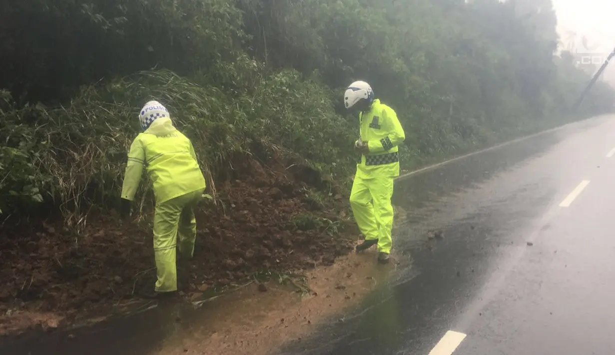 Petugas kepolisian memeriksa lokasi longsor yang terjadi di kawasan Puncak Bogor, Jawa Barat (5/2). Menurut Hasby, kondisi badan jalan tertutup karena tanah turun dari gunung sepanjang 20 meter. (Foto: Lantas Bogor)