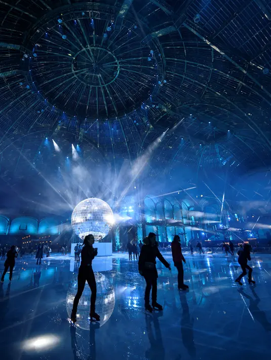 Orang-orang berseluncur di arena ice skating di bawah kubah kaca mewah legendaris, Grand Palais, Paris, Selasa (17/12/2019). Arena ice skating musiman ini menjadi yang terbesar di Prancis, dan satu magnet wisata sepanjang tahun. (Photo by Thomas SAMSON / AFP)