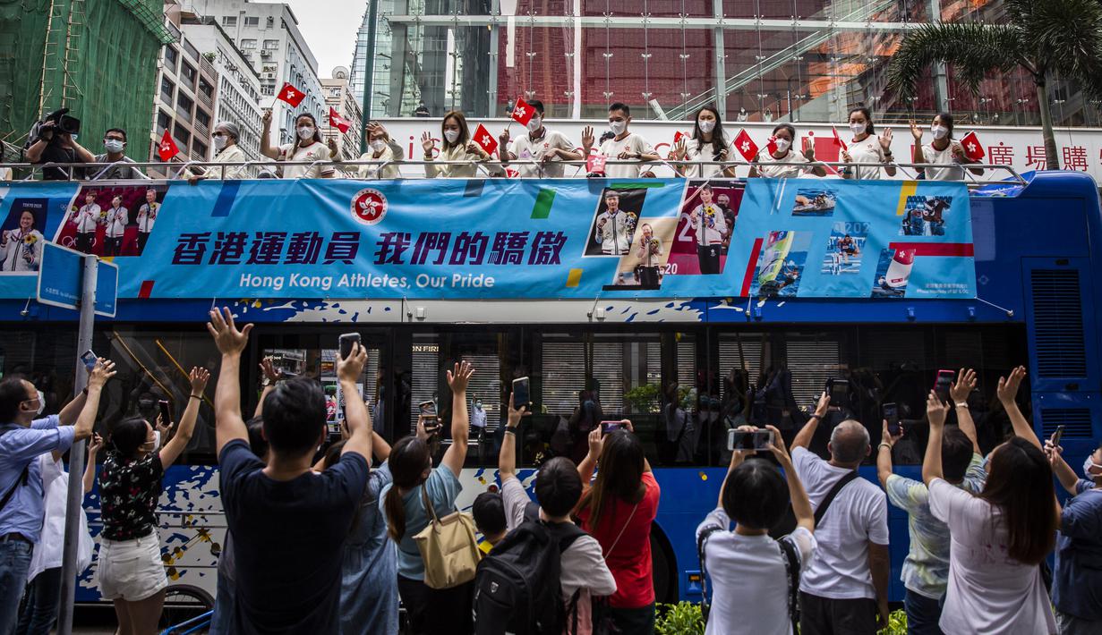 Anggota delegasi Olimpiade Hong Kong mengibarkan bendera selama parade bus, setelah Olimpiade Tokyo 2020, di Hong Kong, Kamis (19/8/2021). Hong Kong yang memiliki 46 atlet perwakilan pada Olimpiade Tokyo 2020 berhasil mengumpulkan satu emas, dua perak dan tiga perunggu. (ISAAC LAWRENCE/AFP)