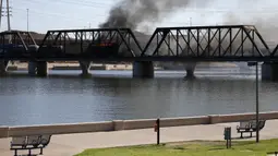 Kereta barang tergelincir dan terbakar di jembatan Danau Kota Tempe, Arizona, Amerika Serikat, Rabu (29/7/2020). Kecelakaan memicu kebakaran hebat dan terlihat beberapa kilometer. (AP Photo/Ross D. Franklin)