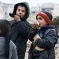 Dua orang anak makan roti sambil menunggu untuk dievakuasi dari sektor yang dikuasai pemberontak, Aleppo, Suriah (9/12). (REUTERS / Abdalrhman Ismail)