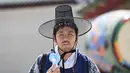 Seorang turis yang mengenakan pakaian tradisional Hanbok menggunakan kipas portabel untuk mendinginkan diri di Istana Gyeongbokgung di Seoul, Korea Selatan, Senin,  3 Agustus 2026. (AFP/  Jung Yeon-je)