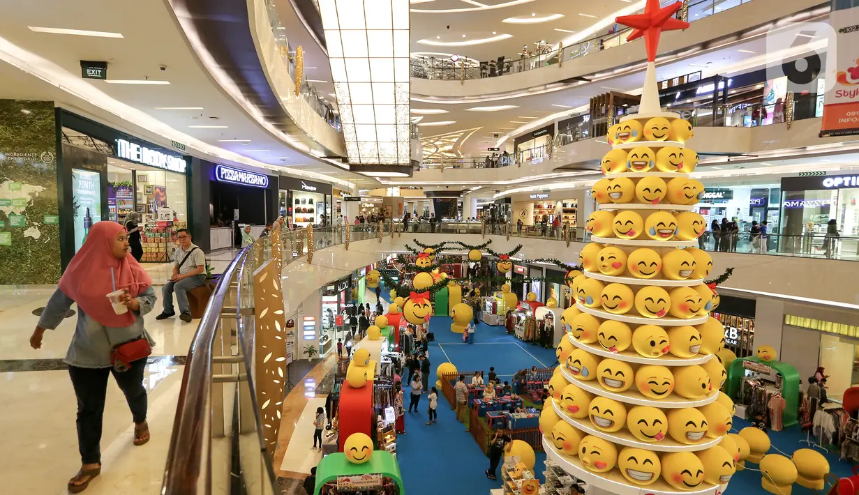 Pengunjung melintas di samping pohon Natal yang didominasi warna kuning setinggi 12 meter di Lippo Mall Kemang,  Jakarta Sabtu (14/12/2019). Pohon dengan konsep Joypixels Emoji momentum liburan menyambut Natal bersama keluarga. (Liputan6.com/Fery Pradolo)