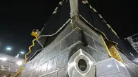 Petugas saat mengganti kain penutup Ka'bah (Kiswah) dengan yang baru di Masjidil Haram, kota suci Makkah, Arab Saudi (18/7/2021). Pergantian Kiswah rutin dilakukan pada musim haji, tepatnya pada 9 Zulhijah. (AFP Photo)