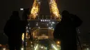 Awak media berdiri di depan Menara Eiffel dengan tulisan 'Merci" (terima kasih) yang terpampang di Paris, Jumat (27/3/2020). Menara Eiffel menampilkan pesan dukungan dan terima kasih kepada tenaga kesehatan di Prancis yang berada di garda depan memerangi pandemi COVID-19.  (AP/Thibault Camus)