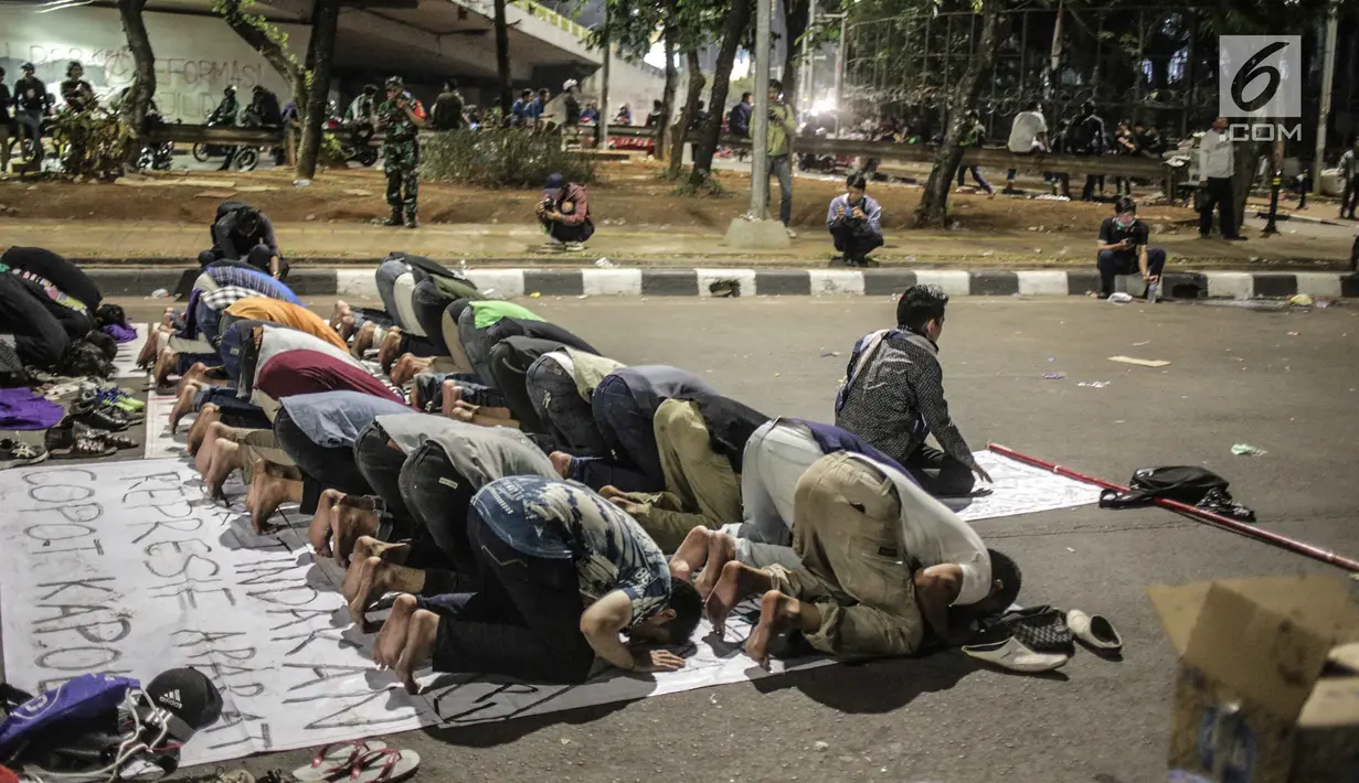 Massa dari Badan Eksekutif Mahasiswa Seluruh Indonesia (BEM SI) melakukan salat magrib disela unjuk rasa di depan gedung DPR/MPR RI, Jakarta, Selasa (1/10/2019). Di sela-sela agenda pelantikan anggota baru DPR RI 2019-2024, gelombang mahasiswa kembali menggelar demo. (Liputan6.com/Faizal Fanani)
