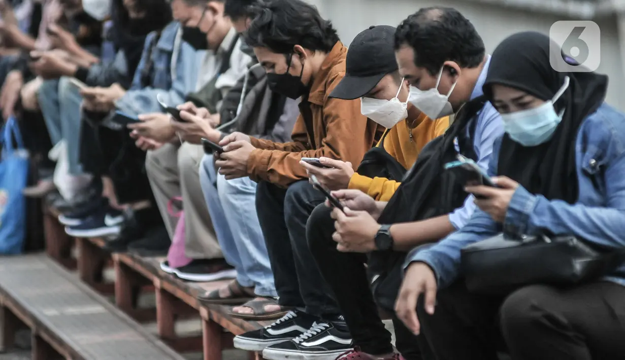 Pekerja memainkan smartphone saat menunggu kedatangan KRL di Stasiun Manggarai, Jakarta, Senin (27/12/2021). Pemprov DKI resmi menetapkan upah minimum provinsi (UMP) 2022 naik 5,1 persen atau menjadi Rp4.641.854. (merdeka.com/Iqbal S Nugroho)
