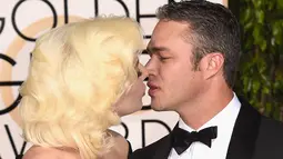 Penyanyi Lady Gaga dan sang tunangan, Taylor Kinney saling berciuman dengan mesra saat ditengah-tengah sesi foto ajang penghargaan film tahunan, Golden Globes 2016 di Beverly Hilton Hotel, California, Minggu (10/1). (Jason Merritt/Getty Images/AFP)