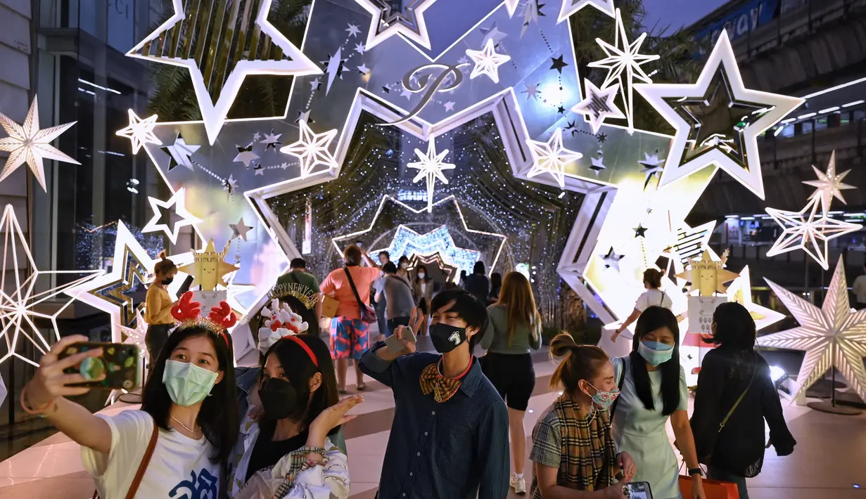 Orang-orang berfoto dengan dekorasi Natal di depan pusat perbelanjaan di Bangkok (21/12/2021). Menyambut Natal, dekorasi unik dan lucu ditampilkan di depan pusat perbelanjaan di Bangkok. (AFP/Lillian Suwanrumpha)