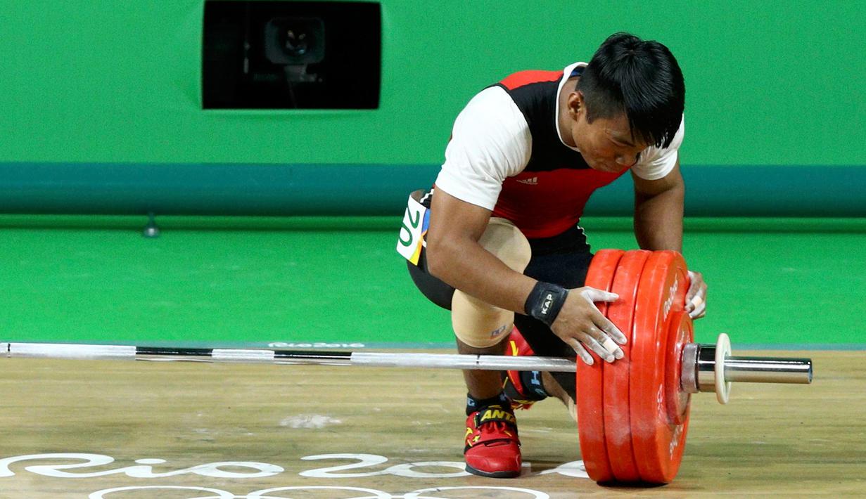 Deni melihat barbel yang gagal diangkatnya saat berlaga di Olimpiade 2016, Brasil, Rabu (10/8). Deni yang memiliki berat tubuh 69.38kg, tidak bermain di kelasnya, dan lawan-lawannya memiliki tubuh jauh lebih berat. (REUTERS/Athit Perawongmetha)