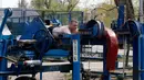 Seorang pria sedang berlatih di outdoor gym atau pusat kebugaran terbuka di tepi Sungai Dnipro, Kiev, Ukraina, Kamis (18/4). Ada lebih dari 200 alat fitness di pusat kebugaran yang berdiri sejak tahun 1970-an ini. (AP Photo/Efrem Lukatsky)