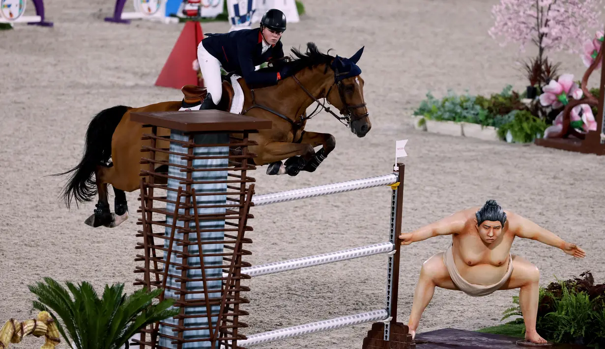 Harry Charles dari Inggris mengendarai Romeo 88 melompati patung sumo kecil saat bertanding di final individu lompat berkuda selama Olimpiade Tokyo 2020 di Equestrian Park di Tokyo (4/8/2021).
(AFP/Behrouz Mehri)