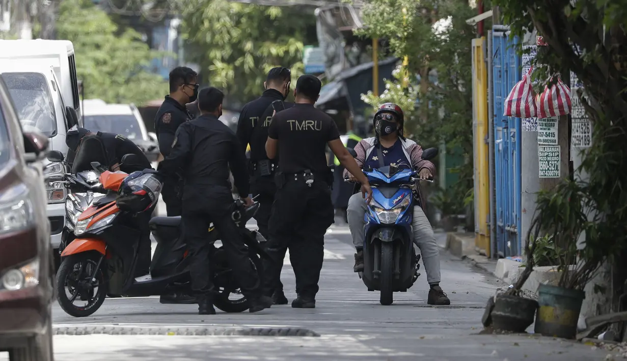 Polisi berbicara dengan seorang warga di sebuah desa yang dikunci karena jumlah kasus COVID-19 di antara warga di Manila, Filipina (11/3/2021). Polisi juga tidak mengizinkan kedua hotel itu selama tiga hari penguncian dan pelanggar akan dipaksa menjalani karantina 14 hari. (AP Photo/Aaron Favila)