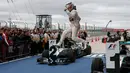 Pembalap Mercedes, Lewis Hamilton melompat usai memenangkan Grand Prix F1 Amerika Serikat di Sirkuit The Americas, Minggu (25/10). Ini merupakan gelar juara dunia ketiga bagi Hamilton setelah sebelumnya diraih pada 2008 dan 2014. (REUTERS/Adrees Latif)