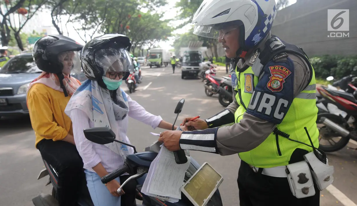 Anggota Satlantas Polres Tangerang Selatan memeriksa kelengkapan surat saat razia pajak kendaraan di Jalan BSD, Tangerang Selatan, Kamis (24/1). Razia juga untuk meningkatkan tertib lalu lintas dan disiplin pengendara bermotor. (Merdeka.com/Arie Basuki)
