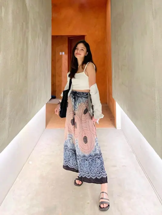 <p>White shirt yang dijadikan outer dengan inner berwarna senada cocok untuk dipadu padankan dengan celana kulot batik berbahan rayon merupakan outfit liburan ke Bali yang nyaman.&nbsp;(instagram/bellagap)</p>